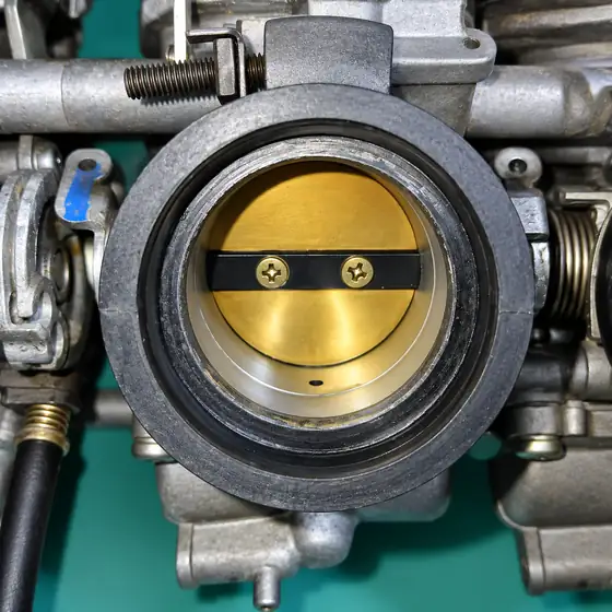 Close-up of a throttle body with its brass butterfly valve